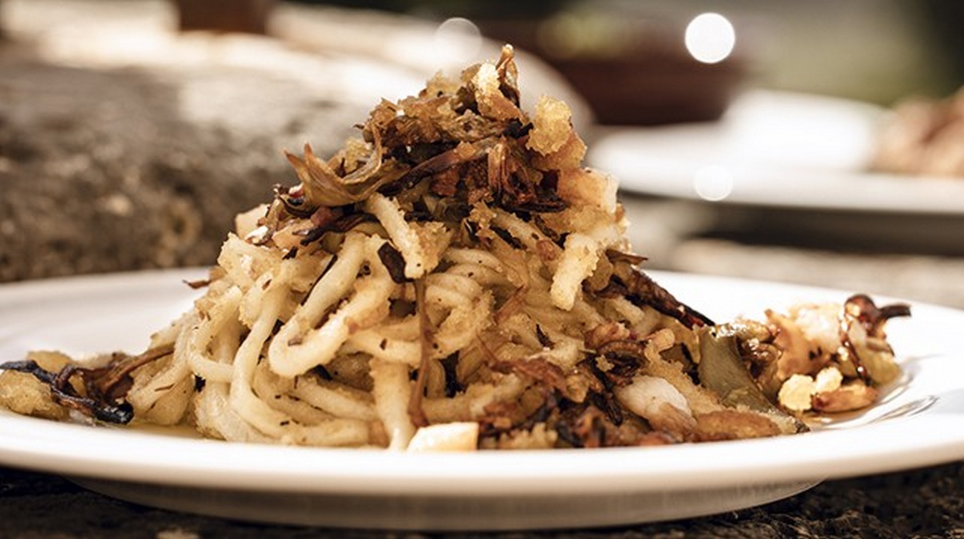 Piatto di pici con briciole, guanciale croccante e carciofi trifolati, tipica specialità toscana a Montepulciano